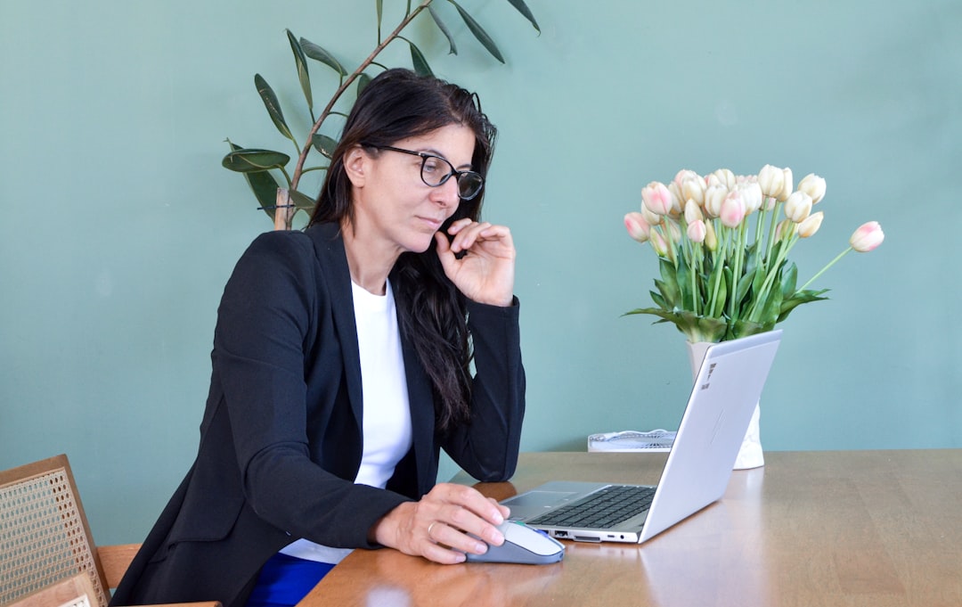 Woman in glasses working on laptop at desk