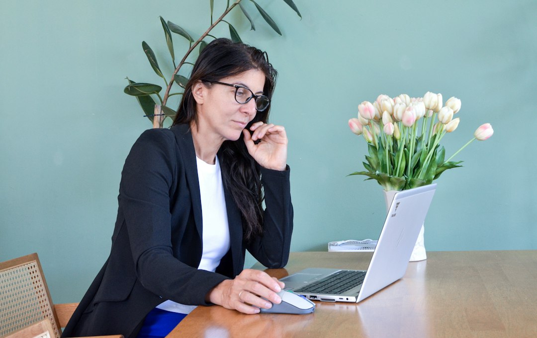 Woman in glasses working on laptop at desk